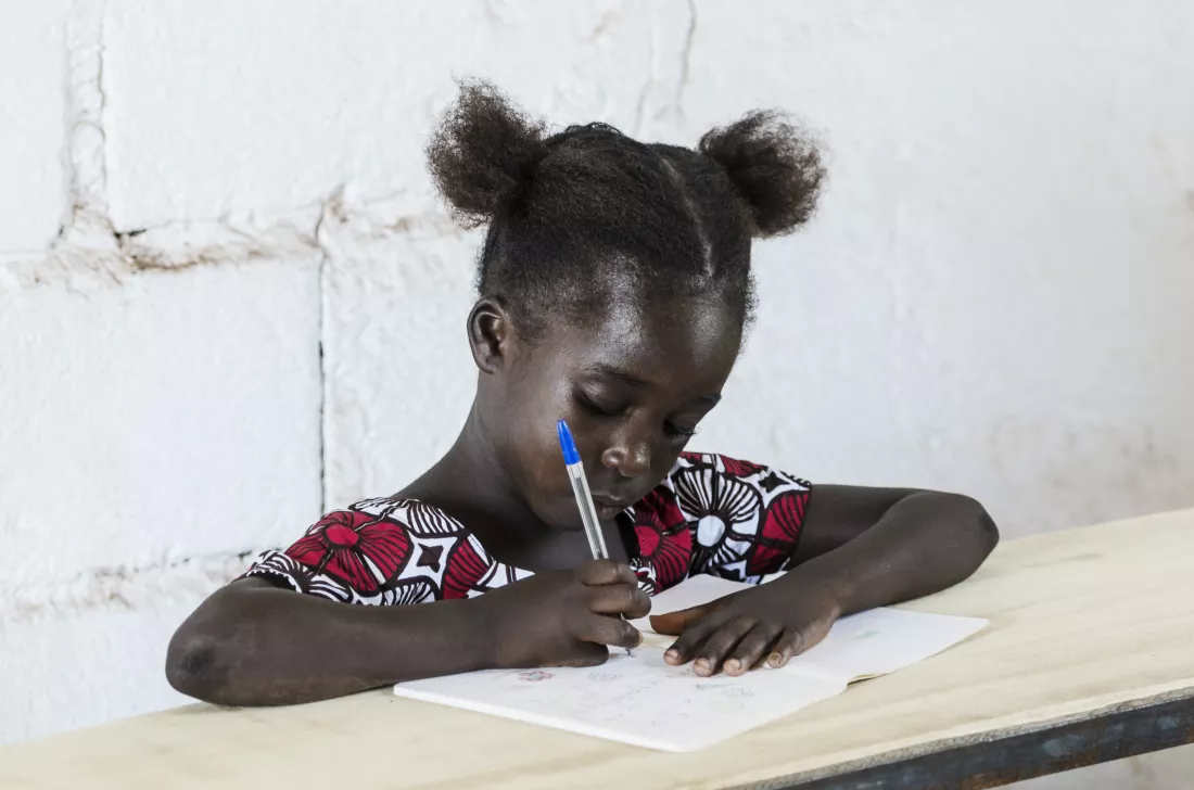 girl-writing-while-sitting-table-against-wall